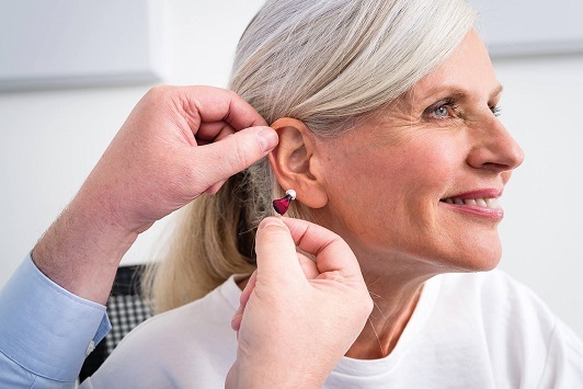 Ältere Frau erhält ein Hörgerät zur Hörverbesserung durch einen Hörakustiker.